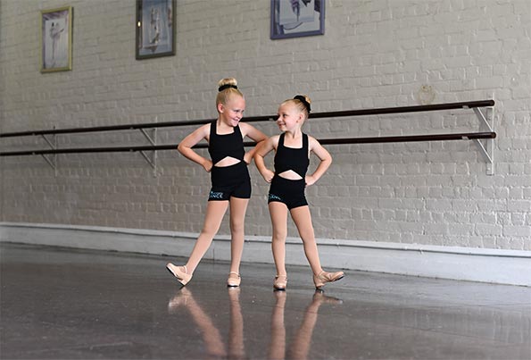 Two young dancers sharing a laugh in class